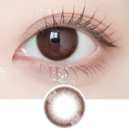 Close-up shot of model's eye adorned with Ann365 JUST MAX Choco daily color contact lenses with prescription, paired with clean-girl eye makeup, showing the brightening and enlarging effect of the circle contact lens on dark brown eyes, above a cutout of the contact lens with limbal ring on a white background.